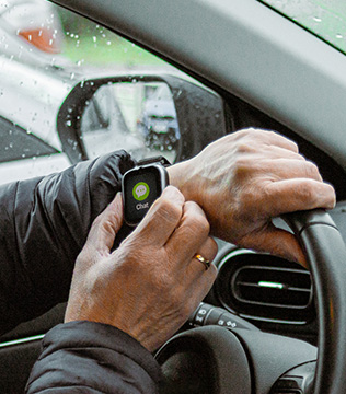 Smartwatch myPhone CareWatch LTE na nadgarstku kierowcy, z ekranem czatu i ręką opartą na kierownicy