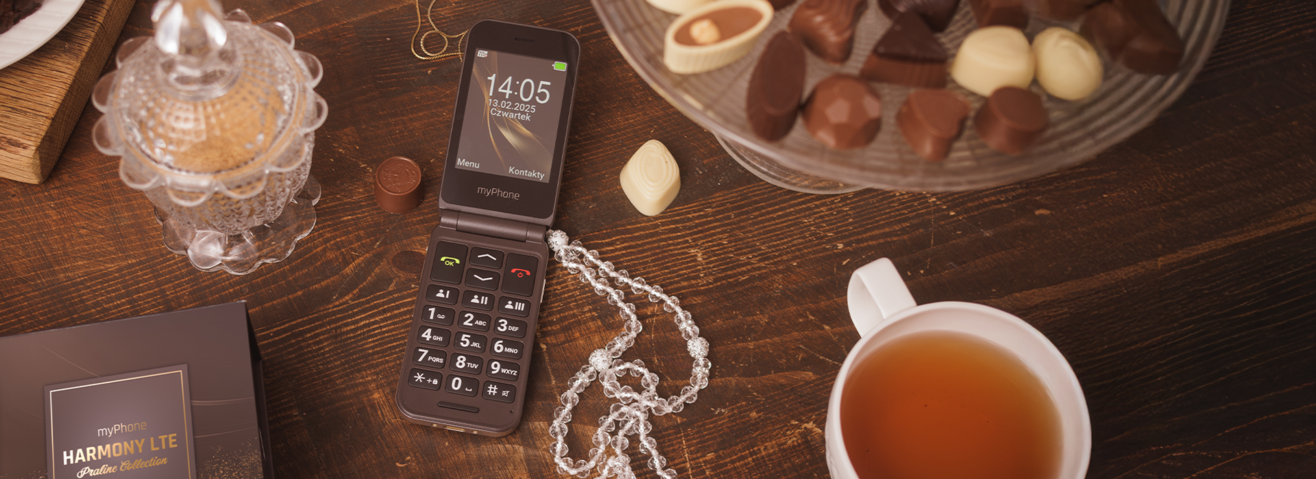 myPhone Harmony LTE Praline Collection na stole.  obok czekoladki na paterze i herbata. Ozdobna cukiernica