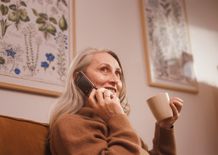 Starsza kobieta trzyma kubek i rozmawia przez telefon myPhone Harmony LTE Praline Collection