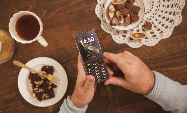 myphone dziadek korzysta z telefonu przy herbacie i cieście